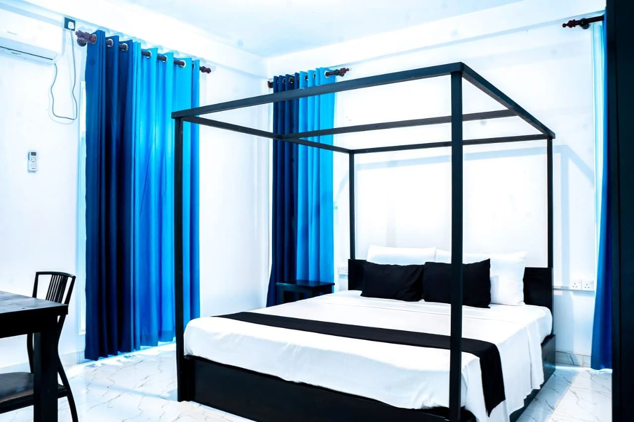 Standard double room with blue curtains and canopy-style bed in Udawalawe